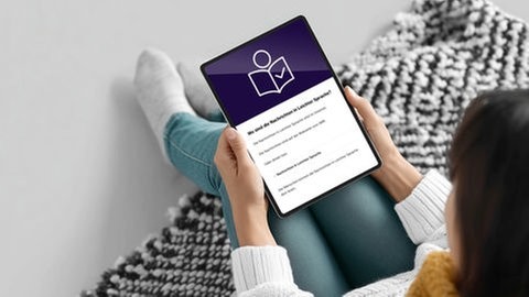 Eine Frau liest die Nachrichten in Leichter Sprache auf ihrem Tablet.