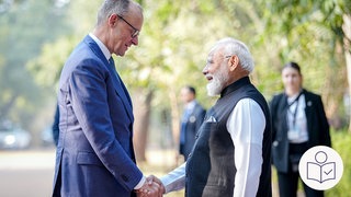 Der deutsche Bundes·kanzler Friedrich Merz und der indische Minister·präsident Modi geben sich die Hand. Sie lächeln. Rechts das SWR Logo für Leichte Sprache.