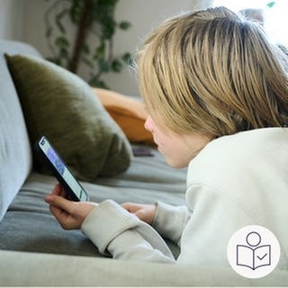 Ein Junge liegt auf einer Couch. Auf dem Bauch liegend schaut er auf ein Handy. Rechts das SWR Logo für Leichte Sprache.
