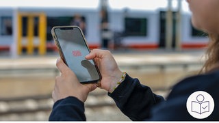 Eine Frau hält ein Handy in der Hand. Auf dem Bildschirm ist das Logo von der Deutschen Bahn. Rechts das SWR Logo für Leichte Sprache.