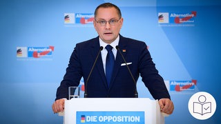 AfD-Chef Tino Chrupalla steht an einem Podium und hält eine Rede. Rechts das SWR Logo für Leichte Sprache.