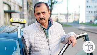 Der Taxi·fahrer Muhammad A. steht an seinem Auto. Die Auto·tür ist offen. Muhammad A. hat einen Auto·fahrer in Mannheim gestoppt. Der Auto·fahrer hat Menschen überfahren.  Rechts das SWR Logo für Leichte Sprache.