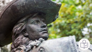 Der Kopf von einer Statue. Die Statue ist von dem französischen Musketier Charles d'Artagnan. Rechts das SWR Logo für Leichte Sprache.