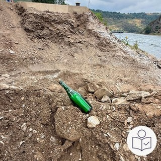 Eine grüne Flasche liegt am Ufer von dem Fluss Rhein. Rechts das SWR Logo für Leichte Sprache.  