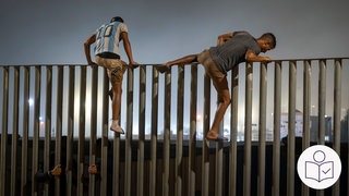 Zwei Männer klettern über einen Zaun. Der Zaun ist der der spanischen Stadt Ceuta. Ceuta liegt im Land Marokko. Rechts das SWR Logo für Leichte Sprache. 