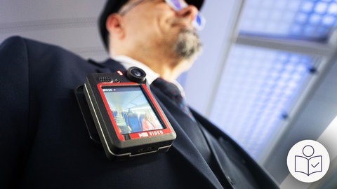 Ein Zugbegleiter in einem Regional·zug der Deutschen Bahn trägt eine Bodycam. Rechts unten das SWR-Logo für Leichte Sprache.