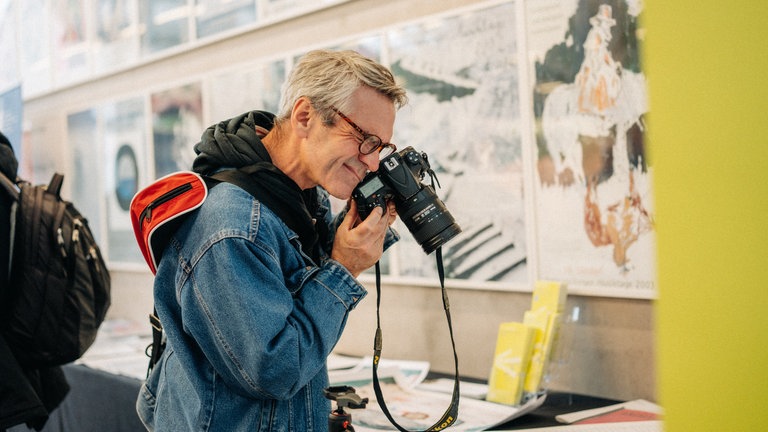 An einem Verlagsstand fotografiert ein Mann die Auslage