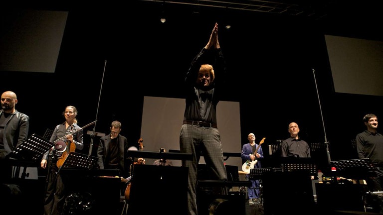 Dirigent in der Mitte des Orchesters bedankt sich