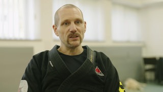 Kampfkunstmeister in einem schwarzen Kampfsport-Anzug.
