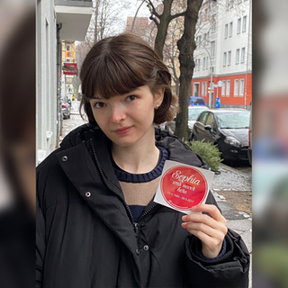 2017 verliert Clara ihre große Schwester Sophia bei einem Reitunfall. Auf dem Foto schaut Clara ernst und zeigt einen Sticker in die Kamera.