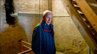 Fritz ist gerade am Treppensteigen im Kirchturm von Görwihl. Man sieht ihn vor einer Treppe und eine Schnur an dem ein Gewicht der Kirchturmuhr hängt.