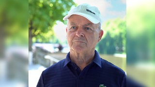 Mann mit Basecap steht vor der Kamera.
