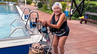 Im Sommer zieht es Else täglich ins Freibad. Mit 101 Jahren steht sie im Badeanzug und gestützt auf ihren Rollator am Beckenrand – und lacht fröhlich in die Kamera.