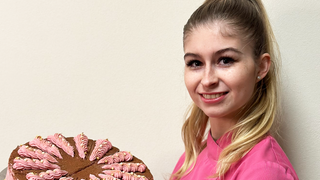 Junge Frau mit blonden Haaren hat Torte in der Hand.