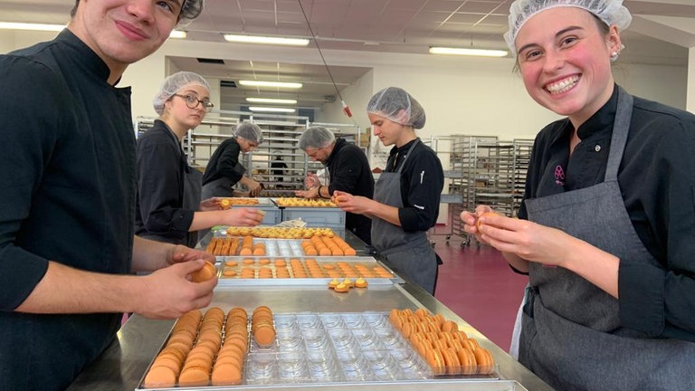 Mehrere junge, in schwarzer Uniform gekleideter Menschen machen Macrons. 