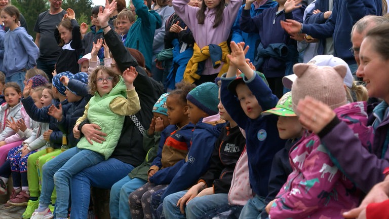 Viele Kinder mit ihren Eltern in einem Park.