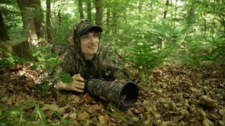 Junger Mann mit Tarnkleidung im Wald liegend