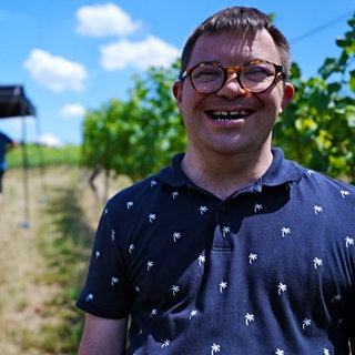Junger Mann mit Down-Syndrom im Weinberg