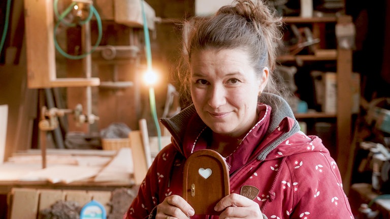 Elli, mittelalte Frau mit braunen Haaren in einer Holzwerkstatt.