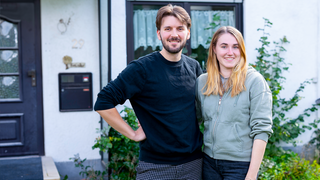 Pascal und Alina stehen vor ihrem Haus. Beide lächeln in die Kamera.