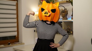 Frau mit orangenfarbiger Kürbismaske auf dem Kopf