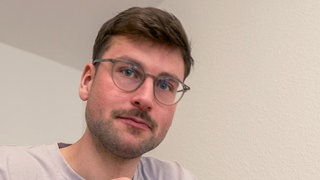 Jona sitzt an einem Esstisch und isst. Er spricht offen über seine Magersucht und darüber, was ihm im Umgang mit der Essstörung geholfen hat.