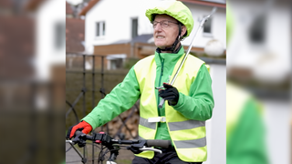 Waldemar ist ehrenamtlicher Müllpate auf der Ostalb. Er ist mit dem Fahrrad in Hussenhofen unterwegs. Er trägt eine gelbe Wanweste und hat seine Greifzange und einen Müllbeutel dabei.