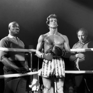 Rocky Balboa steht im Ring vor einem Kampft. Hinter ihm sind seine Trainer zu sehen.
