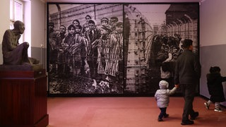 Besucher gehen am 22. Januar 2023 an einem Bild des ehemaligen nationalsozialistischen Konzentrationslagers Auschwitz-Birkenau in Oswiecim vorbei.
