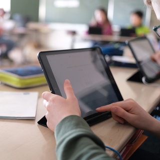 In einer 3. Klasse einer Grundschule lösen Schüler an Tabletts digitale Mathematikaufgaben.