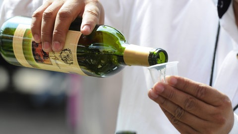Koch gießt Weißwein in einen Becher