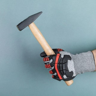 Hand mit Schutzhandschuh hält Hammer. Symbolfoto.