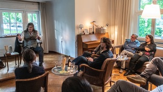 Eine Gastgeberfamilie veranstaltet einen Kulturabend im Wohnzimmer. Symbolfoto.