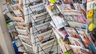 Tageszeitungen stecken in Frankfurt am Main an einem Zeitungsstand in Drehständern. 