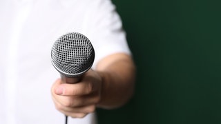 Mann hält Mikrofon und macht ein Interview. Symbolfoto.