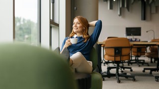 Frau genießt Kaffeepause in modernem Büroambiente. Modelvertrag, Symbolfoto.