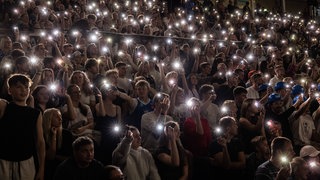 Fans waving mobile flashlights. Symbolfoto.