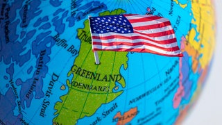 Eine US-Flagge steckt auf einem Globus im Bereich Grönland. 