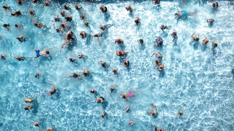 Zahlreiche Badegäste sind in einem Freibad im Wasserbecken (Aufnahme mit einer Drohne).