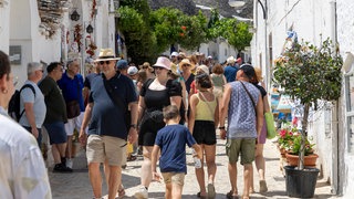 Touristen in Alberobello schauen sich die traditionallen Trulli Häuser an.