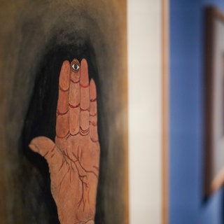Ein Frau steht in der Ausstellung „Menschen die noch hätten leben können“ in den Ausstellungsräumen der Sammlung Prinzhorn neben einem Werk des Künstlers Ludwig Berthold mit dem Arbeitstitel „Hand mit Auge“. 