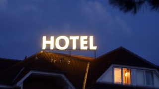 Das Wort Hotel leuchtet auf einem Dach. Symbolfoto.