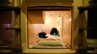 Schlafkabine mit eingebauten Fernseher in einem Kapselhotel. Fernseher, Klimaanlage und Licht werden von einer Konsole aus kontrolliert, die Kabine mit einer Sichtblende verschlossen. Japan. Archivfoto.