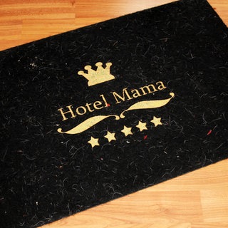Fussmatte mit Aufschrift Hotel Mama und 5 Sterne liegt auf dem Parkett Fussboden. Symbolfoto.