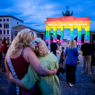 Das Brandenburger Tor wird in Regenbogenfarben illuminiert, wobei der Schriftzug „Berlin, Stadt der Freiheit“ zu lesen ist. Der Christopher Street Day in Berlin war am Vortag abgebrochen worden, nachdem ein Auto am Rande der Großveranstaltung in eine Menschenmenge gefahren war.