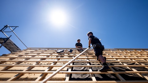 Dachdecker arbeiten unter der sengenden Sonne bei über 30 Grad auf dem Dach eines Hauses.