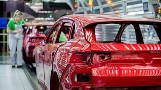 Mitarbeiter überprüfen im Lichttunnel der Lackiererei im Werk von Volkswagen den Lack einer Karosserie.