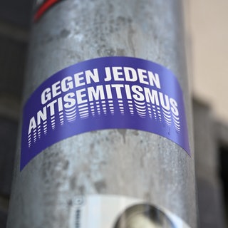 Ein Sticker mit der Aufschrift «Gegen jeden Antisemitismus» hängt an einem Laternenmast in Berlin.
