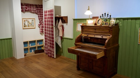 Ein hölzerner Sekretär und ein geöffneter Schrank in der Ausstellung Pettersso, Findus und Co.