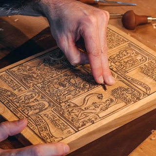 Mit Messern und besonderem Werkzeug hat der dänische Drucker Jorge Larguito einen Druckstock originalgetreu hergestellt und damit eine über 500 Jahre alte Drucktechnik wieder erlebbar gemacht. Als Vorlage diente ihm eine reich illustrierte Seite aus der sogenannten Armenbibel, die im Gutenbergmuseum in Mainz ausgestellt ist.